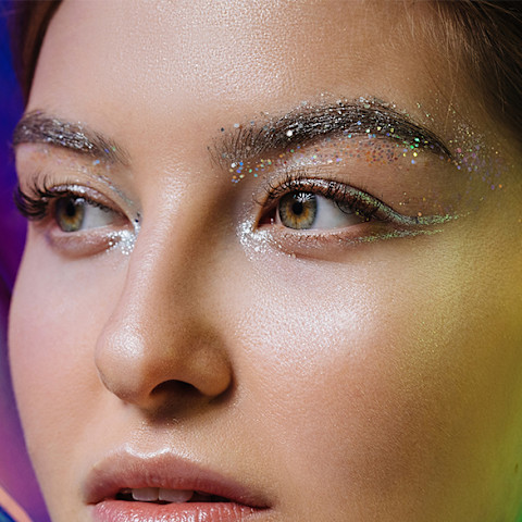 Futuristic portrait of amazing model with seamless skin and silver make up looking away at colorful holographic background Futuristic portrait of amazing model with seamless skin and silver make up looking away at colorful holographic background