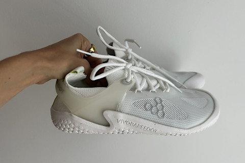 writer's hand holding up the Vivobarefoot Motus Strength shoes
