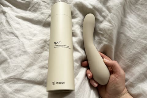 maude spot vibrator held in hand next to cardboard packaging