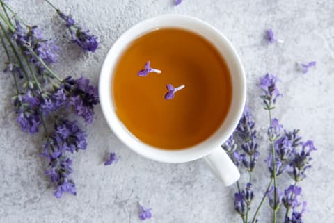 cup of lavender tea on table with petals