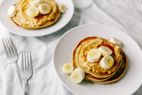 Two Plates Of Vegan Pancakes With Peanut And Banana