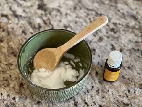 small bowl of white paste on kitchen counter next to essential oil bottle