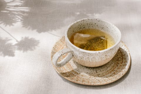 A cup of fresh tea at a picnic outside with reflections of nature