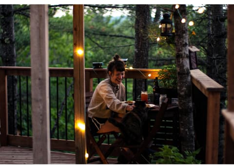 woman and cat eating dinner on porch of remote cabin