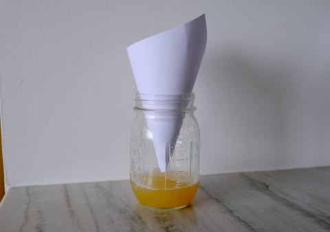 mason jar filled with apple cider vinegar and paper funnel