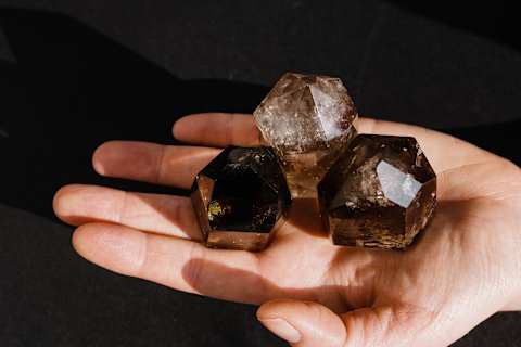 hand holding three pieces of smoky quartz hand holding three pieces of smoky quartz