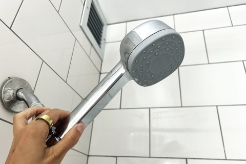 photo of writer's hand holding a handheld showerhead 