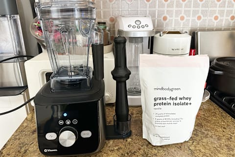 Image of Vitamix Blender next to bag of mindbodygreen protein powder in vanilla