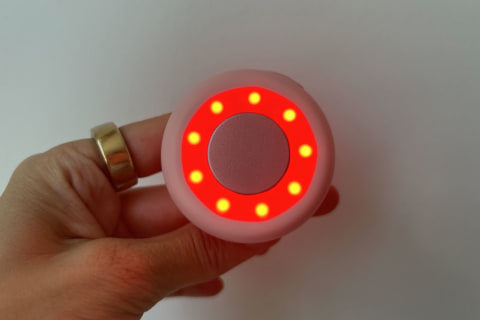 hand holding solawave mini with red light turned on