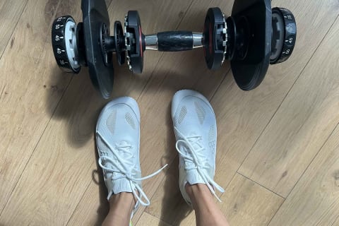 writer's feet in the vivobarefoot motus strength shoes in front of dumbbell