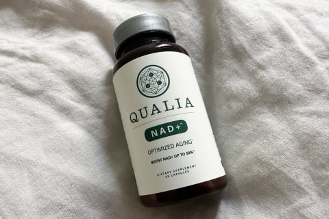 Qualia NAD+ bottle on a linen bedspread in room