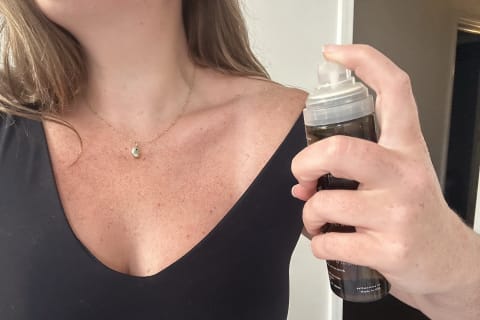 Author spraying soft services clearing mist on neck and chest