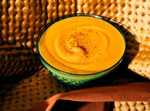 Pumpkin soup on golden velvet and tea towel