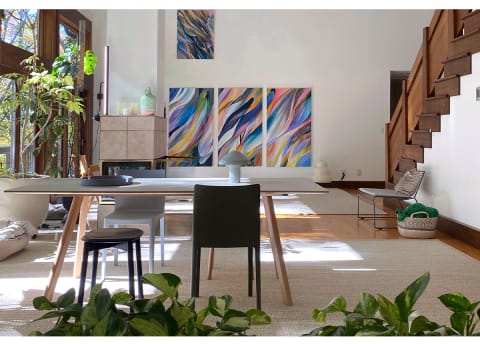 bright dining and living area with abstract art on walls