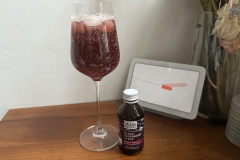 Gaia Herbs Black Elderberry syrup next to a mocktail with sparkling water and syrup