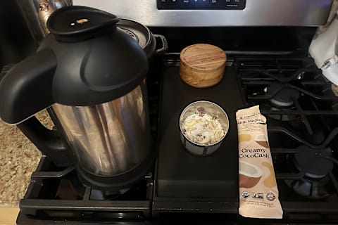 Almond Cow Nut Milk Maker on tester's stovetop with filter basket out filled with Milk Medley