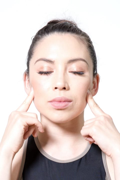 woman massaging cheekbones for tmj using acupressure