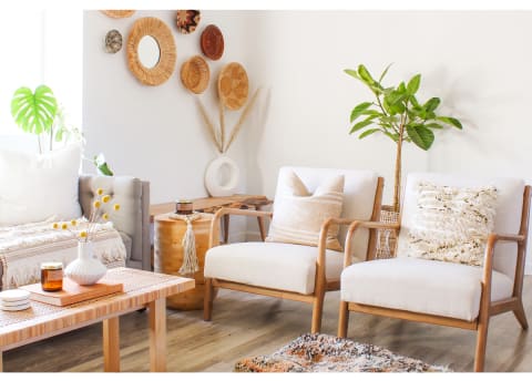 white living room with plants, white chairs, and wicker wall hangings