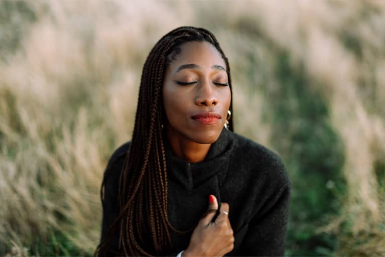 A woman thinking in a field outside.