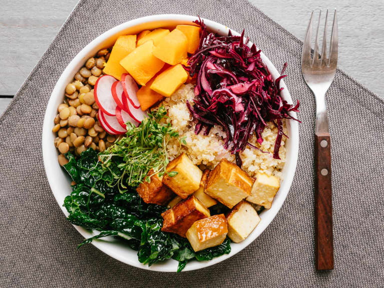 Bowl with healthy vegetabls and tofu. Ingredients: quinoa, lentils, dinosaur kale, smoked tofu, red cabbage, winter squash, radish, cress sprouts