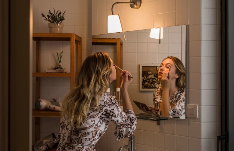 woman applying makeup in the mirror