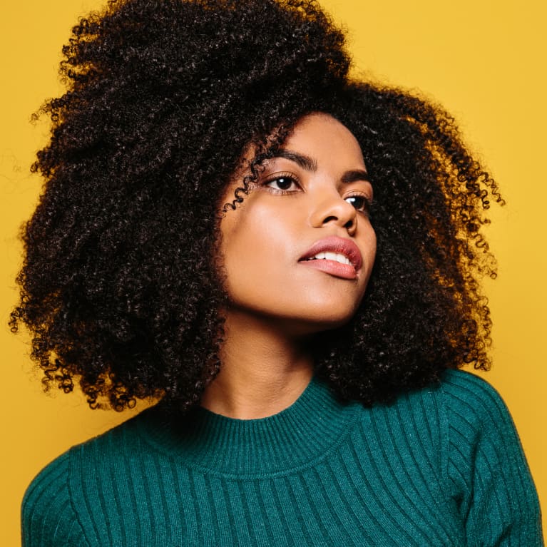 Young Woman with Natural Hair and Glowing Skin on a Yellow Background