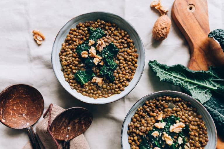 Still life of bowls of lentils with kale and walnuts on kitchen tablecloth / linen