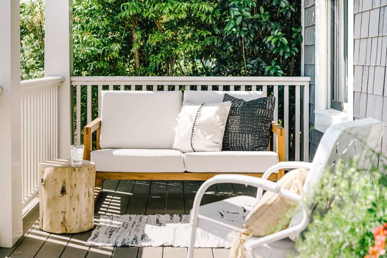 Front porch cottage in the spring with a comfortably styled seating area and blooming potted plants