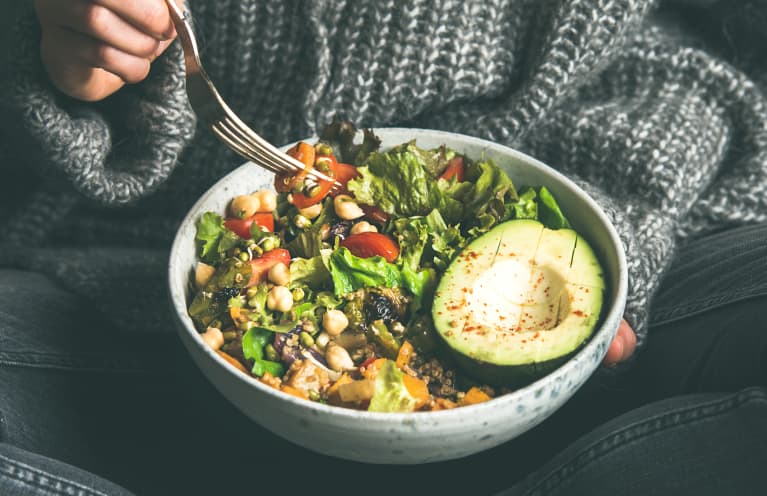 Woman eating fresh salad, avocado, beans and vegetables, square crop