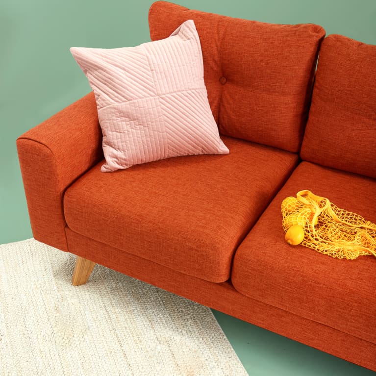 Red Midcentury Couch with Pink Throw Pillow in a Studio