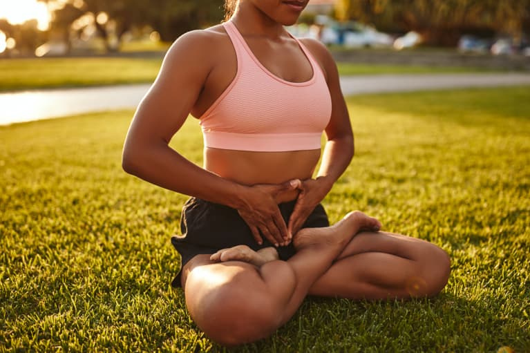 Fit Young Woman In Sportswear Meditating In A Park