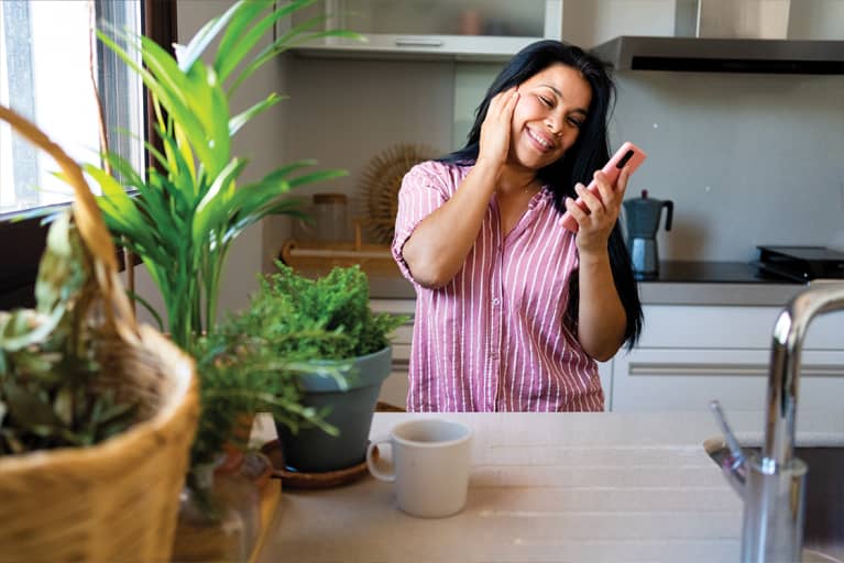 woman in kitchen smiling at phone