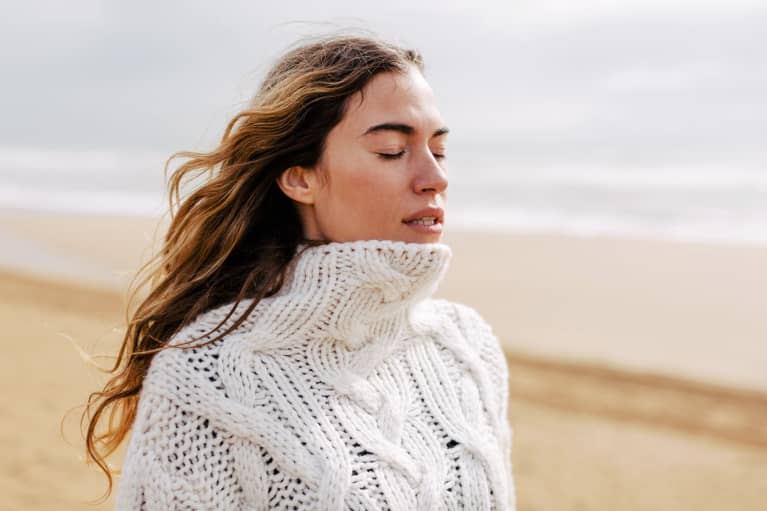 Woman outdoors on beach in sweater during fall / winter