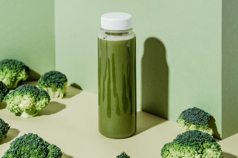 A bottle of green juice and broccoli florets