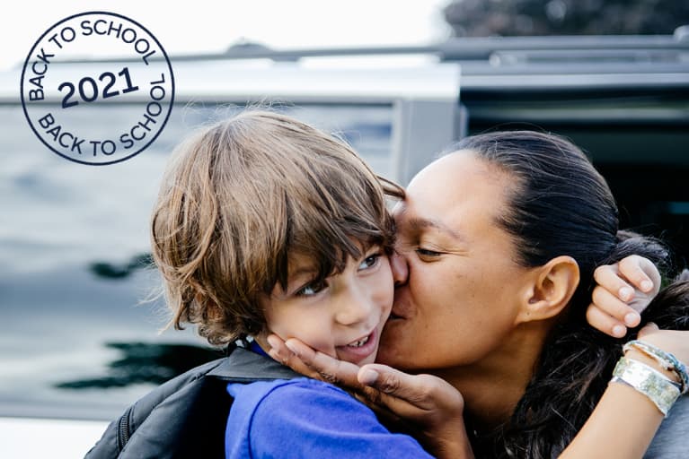 Mother kissing her son on the cheek and cupping his chin with her hand as she drops him off for school. Mother kissing her son on the cheek and cupping his chin with her hand as she drops him off for school.