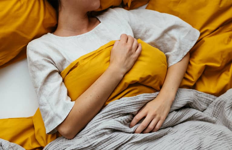 Unrecognizable Woman Sleeping In Bed At Home