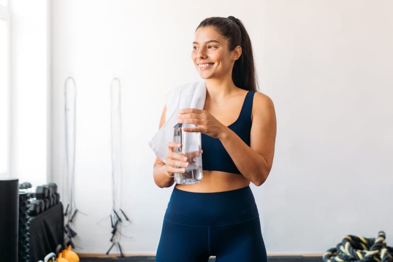 women in workout clothes holding water bottle at gym