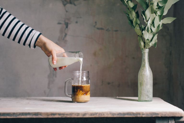 milk pouring into a glass of ice coffee