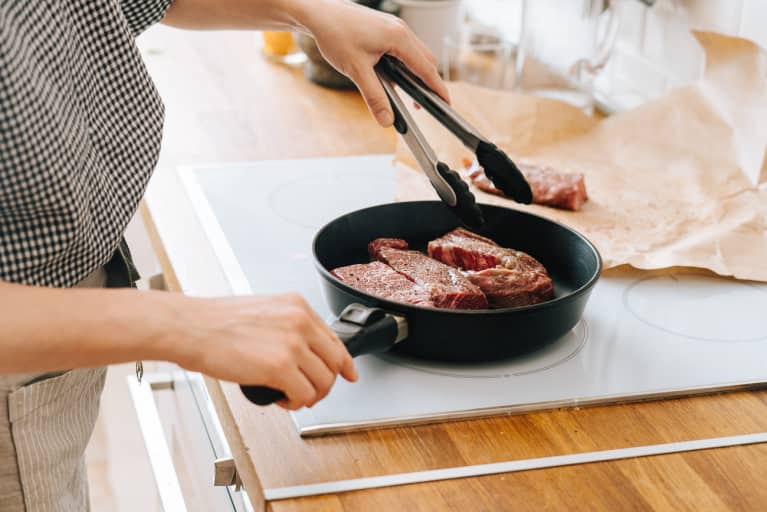 Woman Cooking a Steak in a Cast Iron Skillet