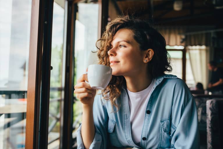 woman drinking coffee looking out window