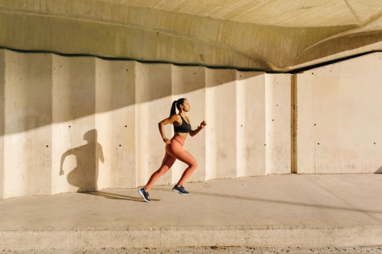 Athletic Woman Running On Street In Sunlight