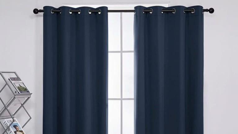 two blackout curtains hanging from window in white room