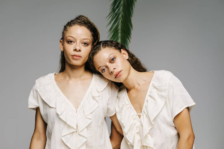 Twins in an embrace on grey background