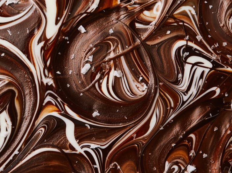 旋转的黑白巧克力的宏观视图，上面覆盖着片状海盐