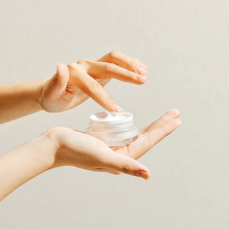 Hands Holding a Container of Facial Moisturizer