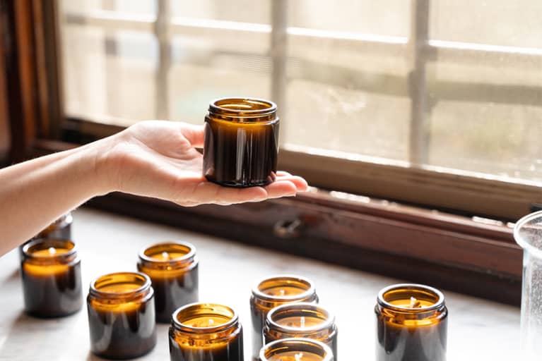 white woman holding homemade candle in amber jar