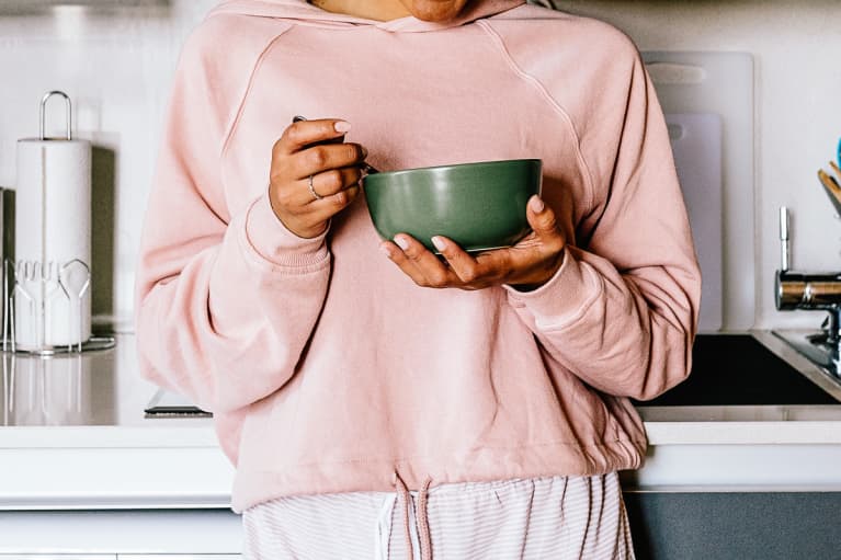 Unrecognizable Woman Eating a Bowl of Cereal In Her Kitchen