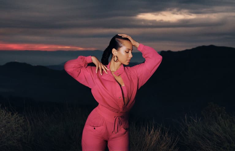 Alicia Keys wearing a pink jumpsuit while the sun is setting