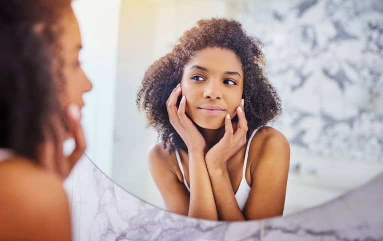 Woman looking in mirror at skin problems