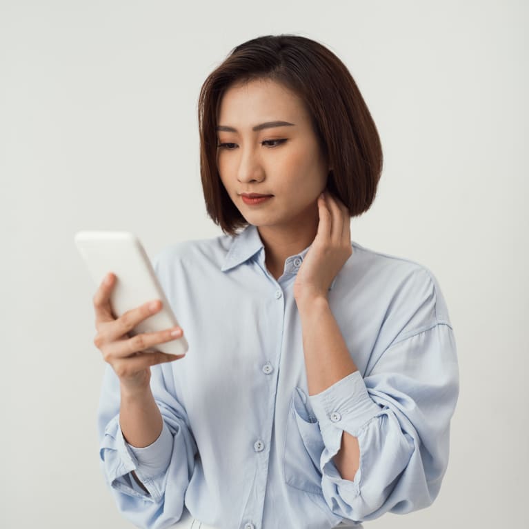 Woman looking at her phone while touching her jaw